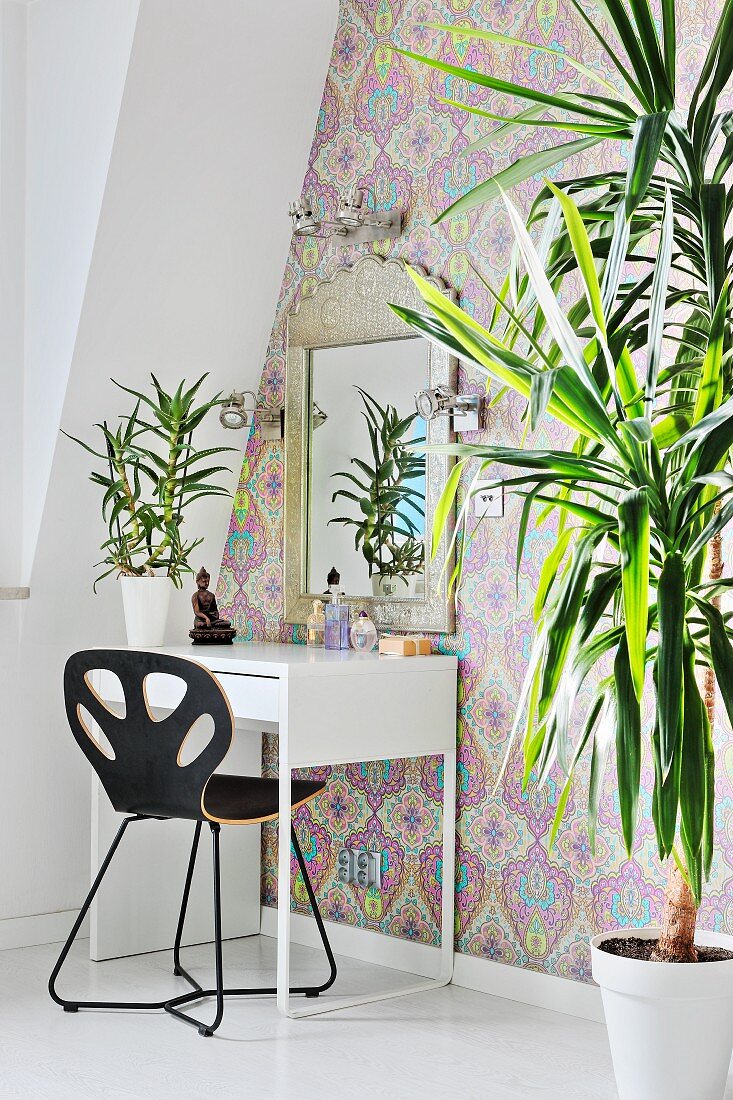 Dracaena and dressing table against patterned wallpaper