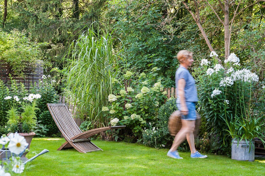 Woman, flowerbeds and lawn in garden