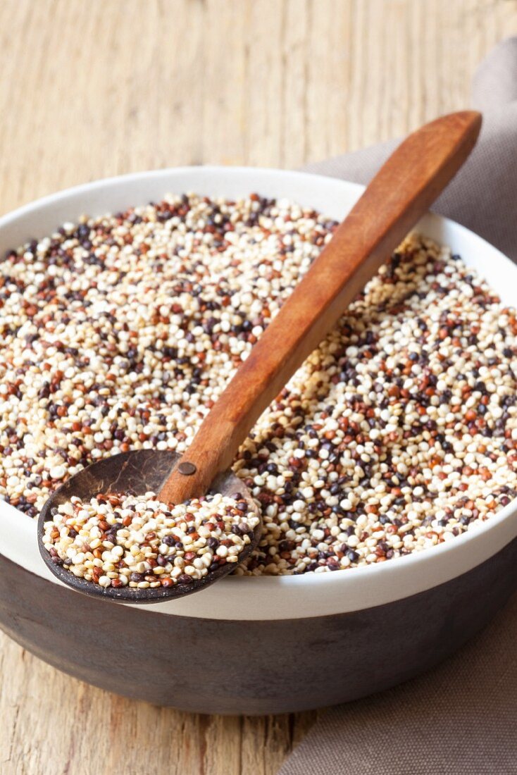 Colorful quinoa in a bowl with a wooden spoon