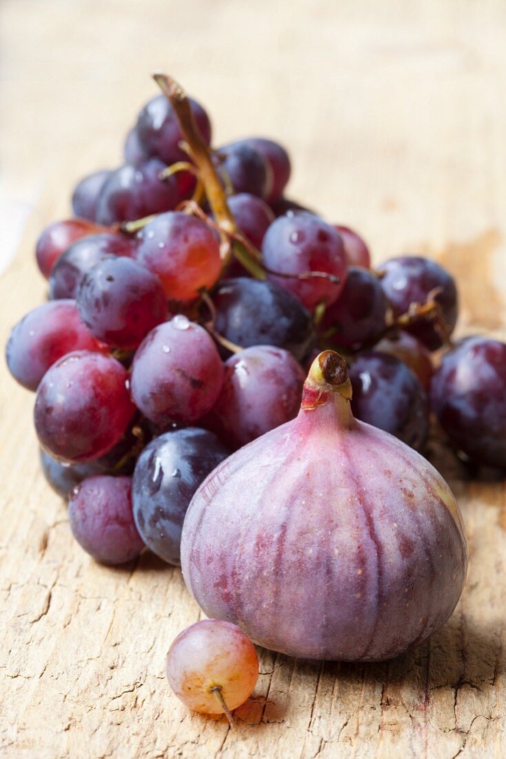 Fresh red grapes and figs on a wooden background