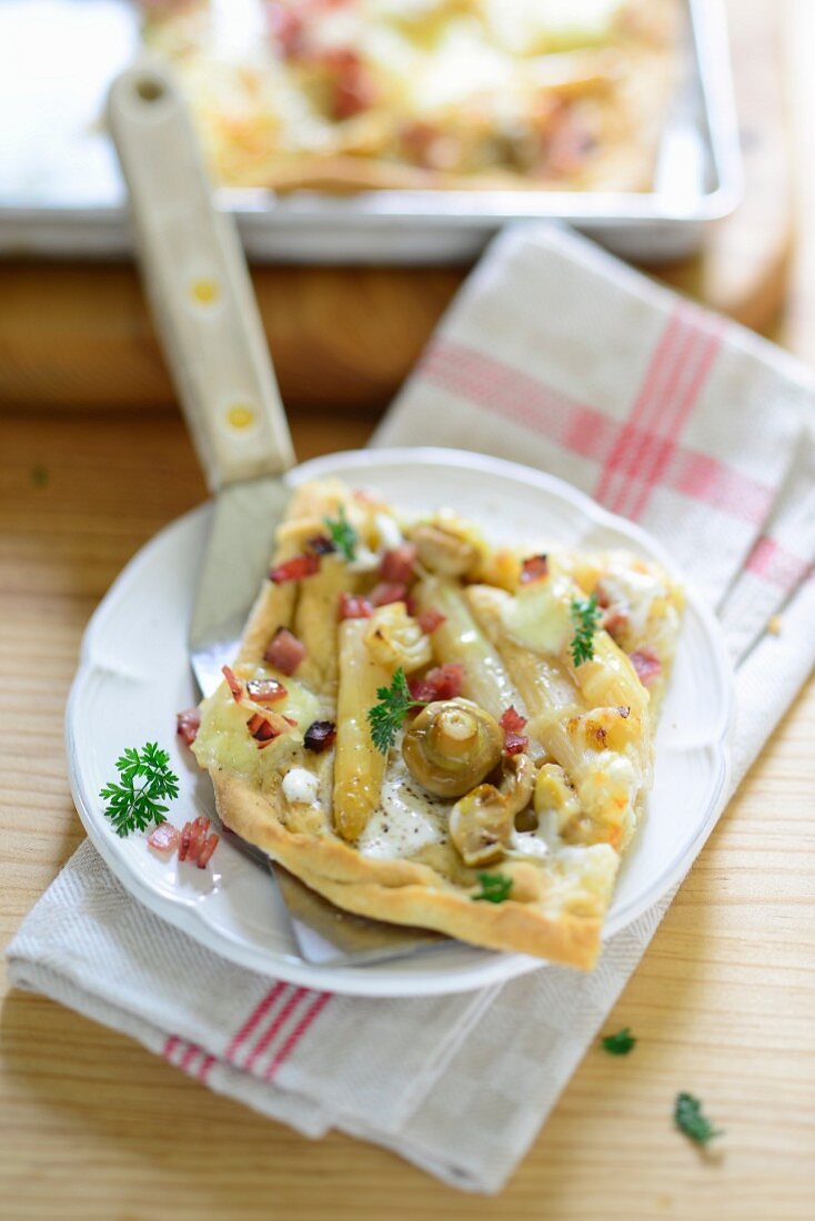 Ein Stück Spargelkuchen mit Champignons und Speck