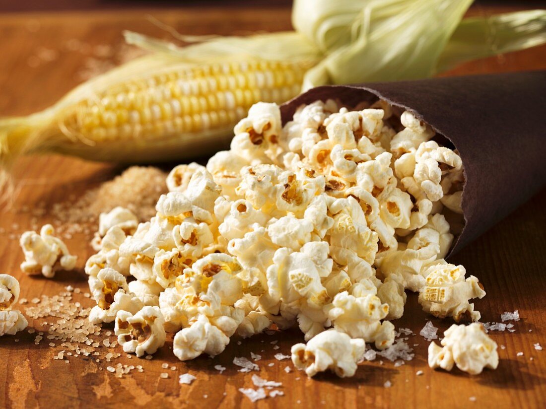 Popcorn, im Hintergrund Maiskolben