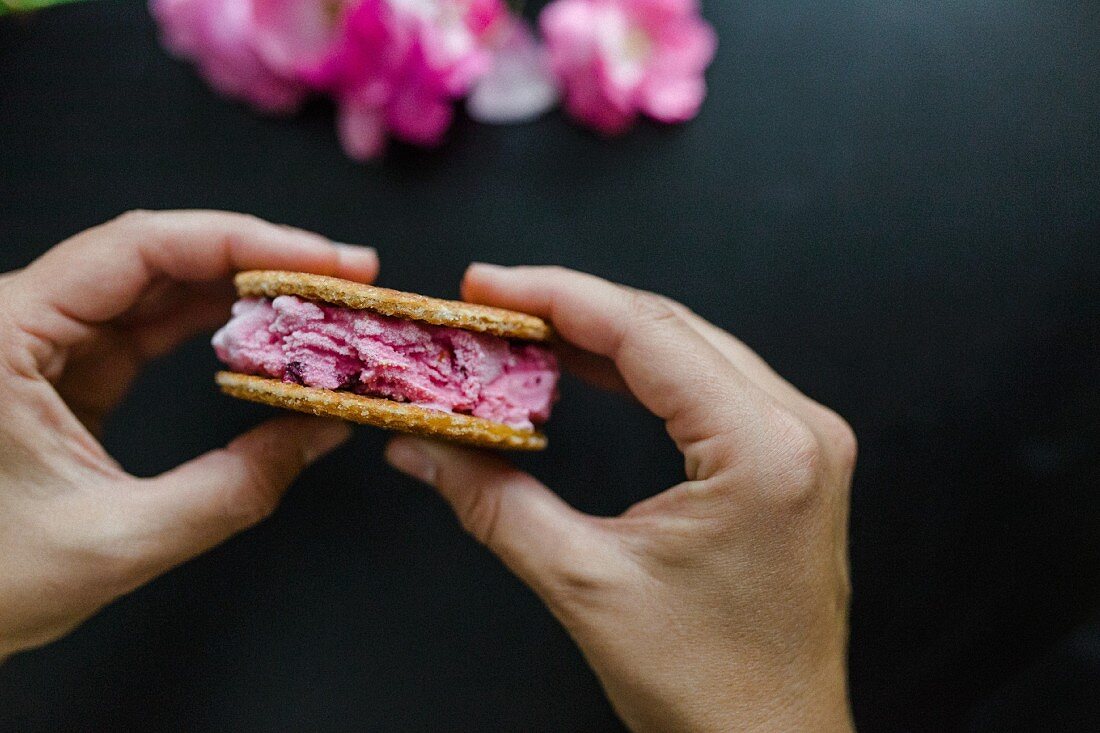 Hands holding cherry ice cream sandwich with waffles