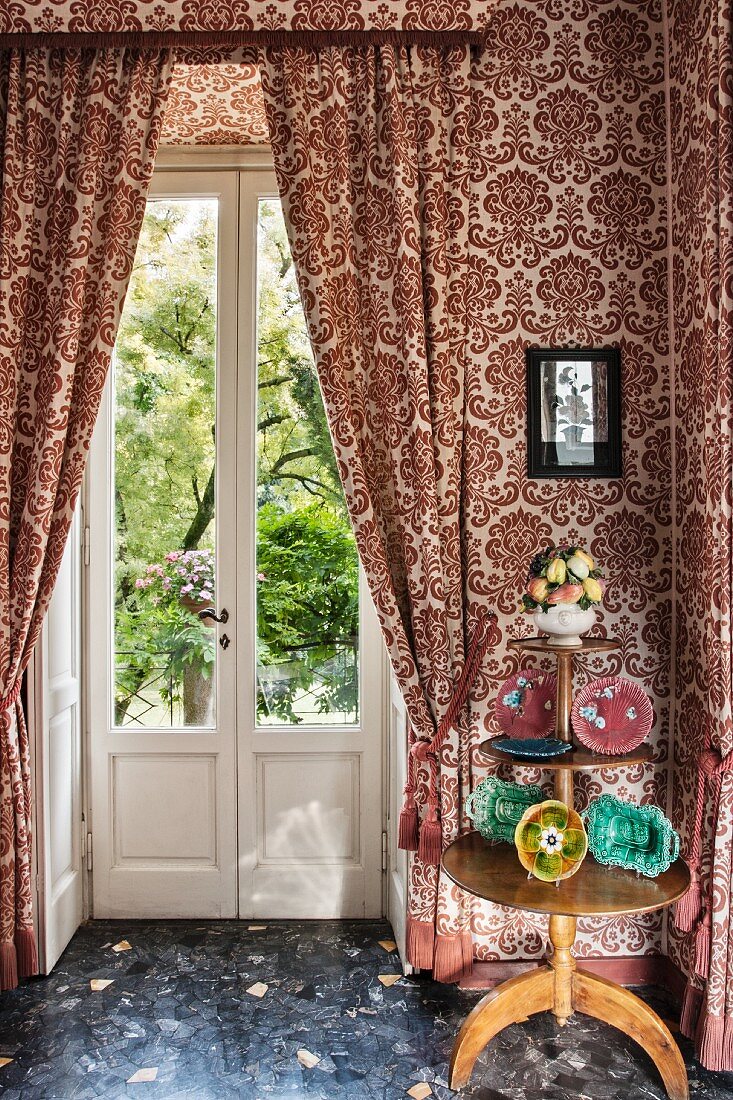 Three-tiered table against patterned wallpaper and matching curtains