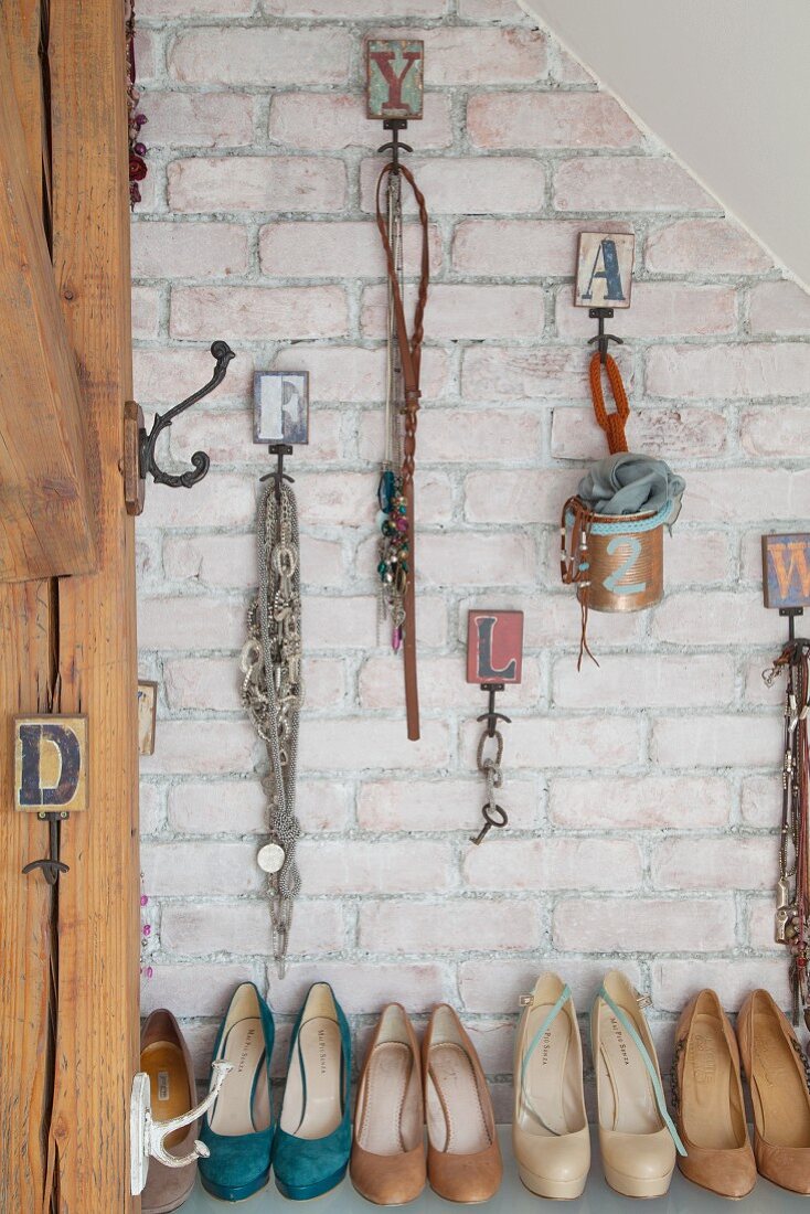 Verschiedene Accessoires und Schmuck mit Vintage Haken an Ziegelwand über Pumps aufgehängt