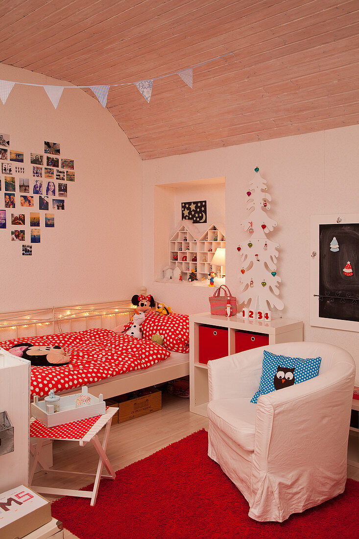 Armchair on rug next to bed in red and white child's bedroom