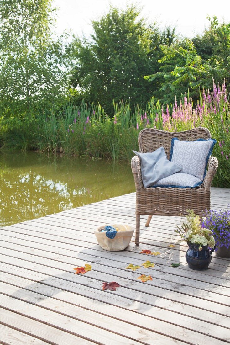 Cushions with crocheted trim on wicker chair on deck next to lake