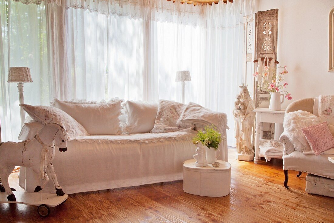 Scatter cushions on white loose-covered sofa in shabby-chic interior