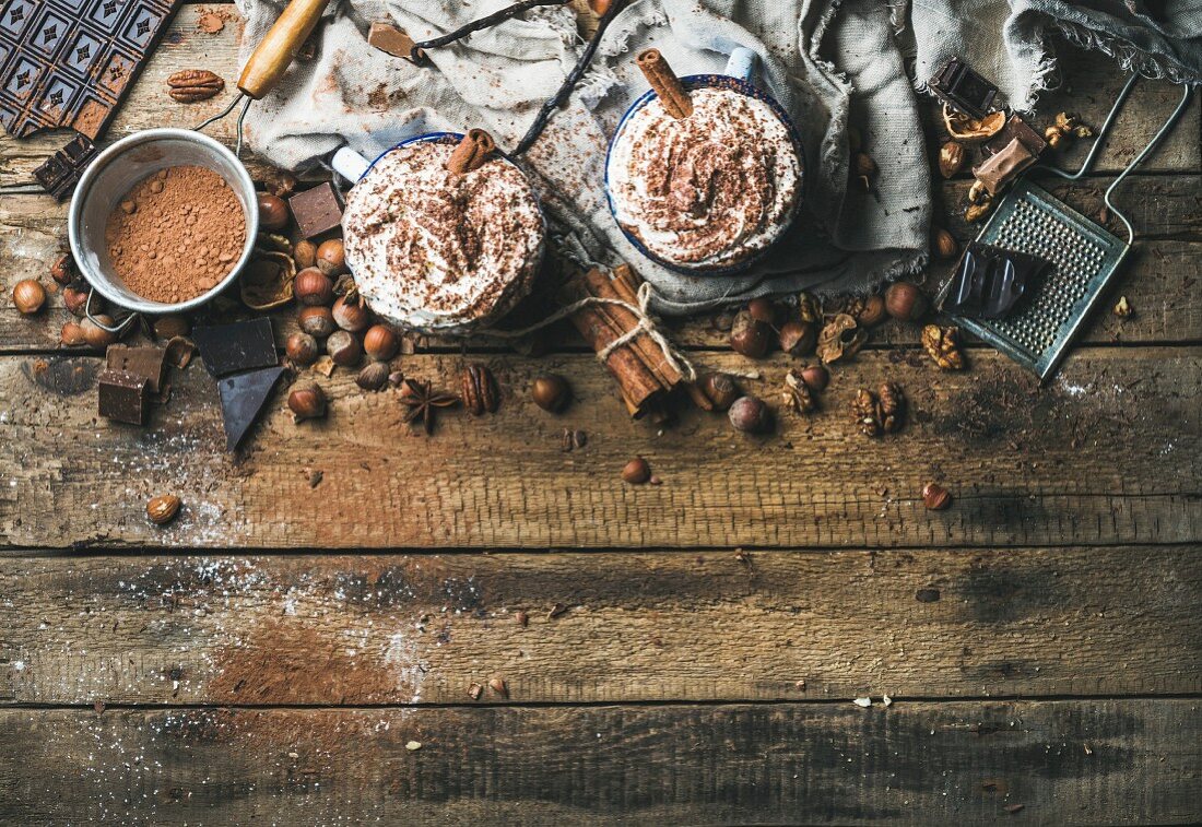 Heiße Schokolade mit Sahne und Zimtstangen auf rustikalem Holzuntergrund