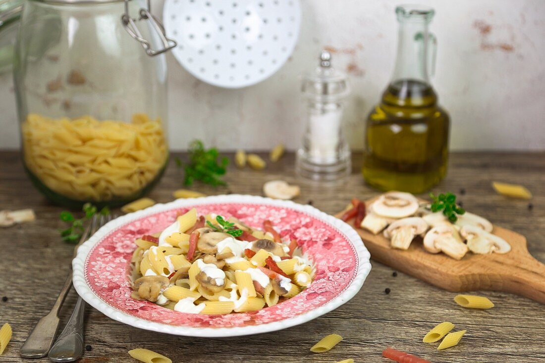 A bowl of penne with cream, bacon and mushrooms