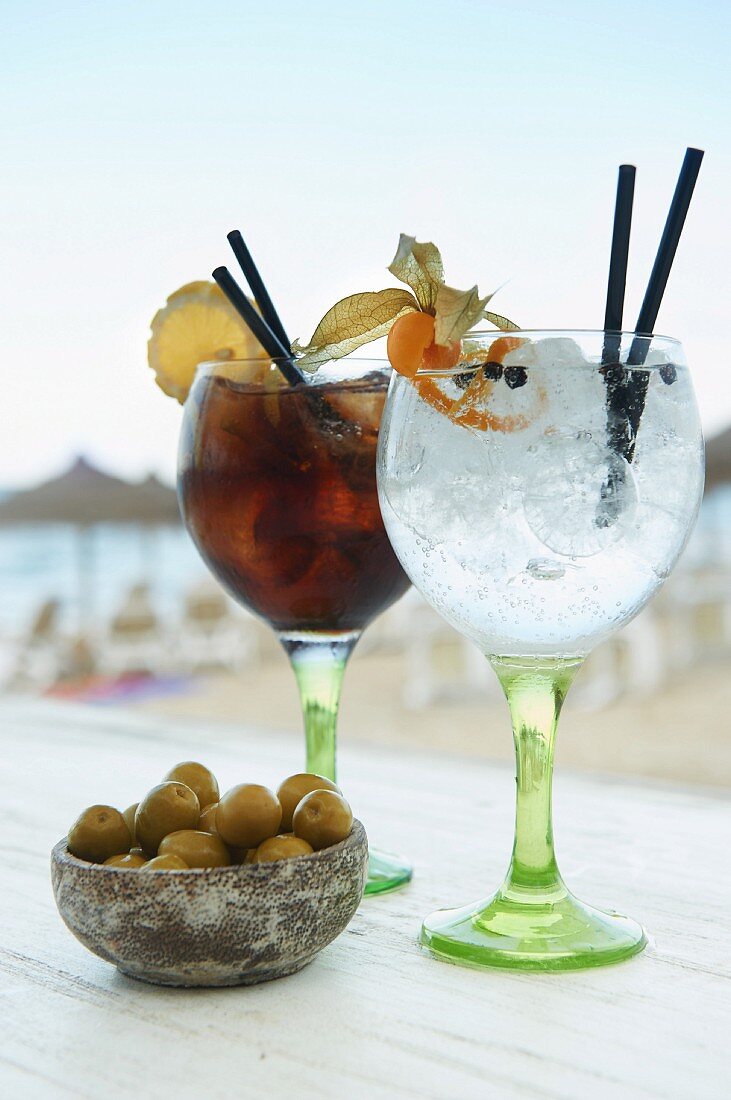 Zwei Gläser mit Gin Tonic und Cola Rum und Schälchen mit Oliven in der 'Ponderosa' Bar, Mallorca, Spanien
