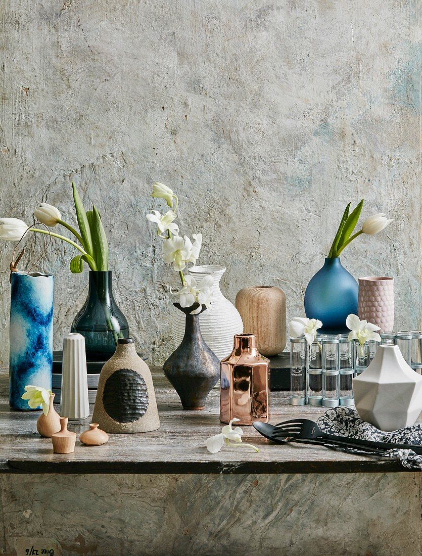 Different vases with white flowers in front of a structure wall