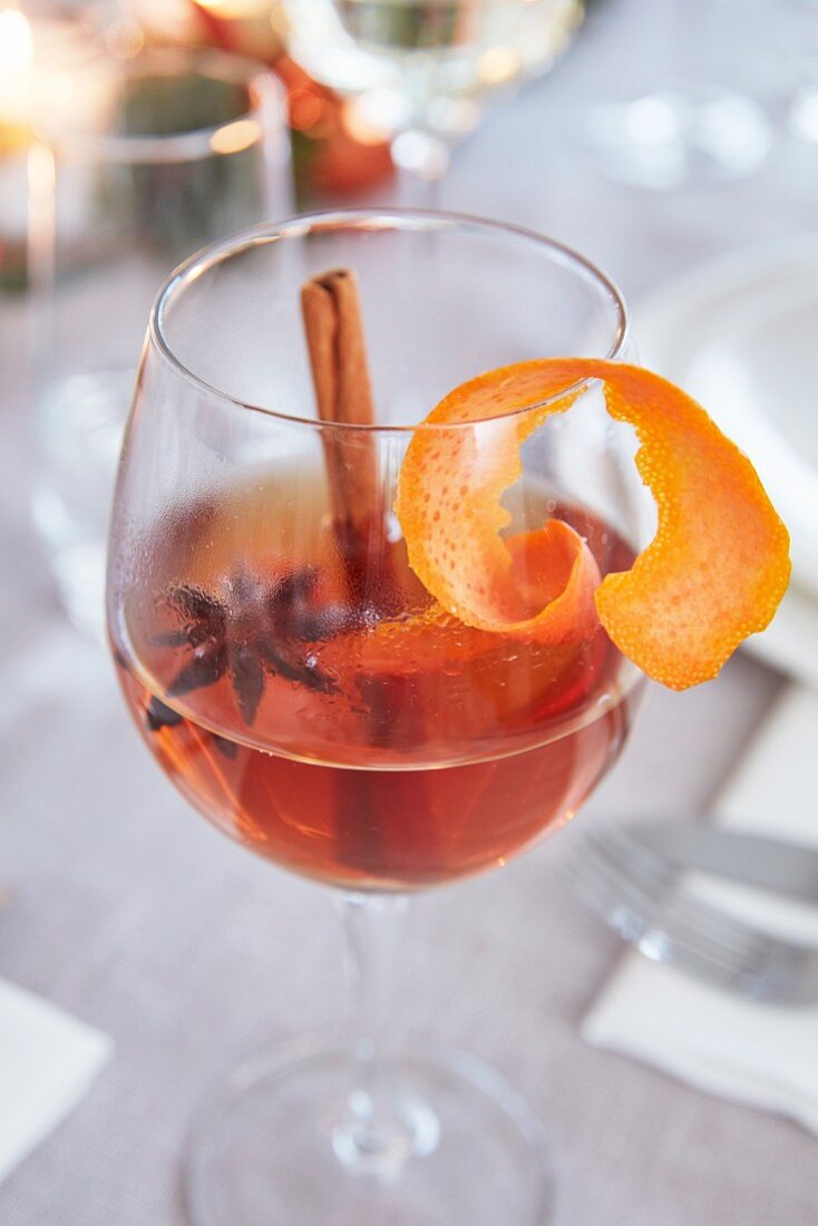 A wine glass of punch with star anise, a cinnamon stick and orange peel