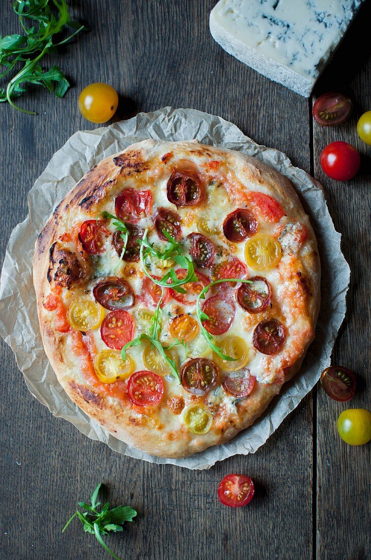 Selbstgemachte Pizza mit bunten Kirschtomaten, Mozzarella und Gorgonzola