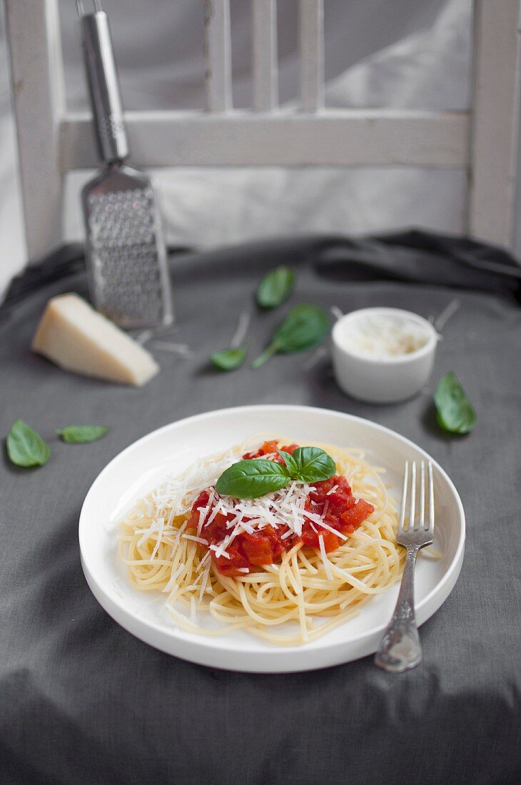 Spaghetti mit Tomatensauce, geriebenem Parmesan und Basilikumblättchen