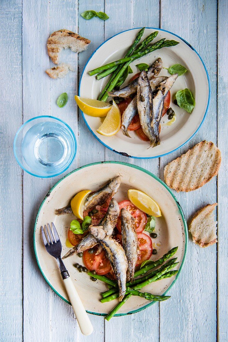 Fried sprats with tomato salad and asparagus