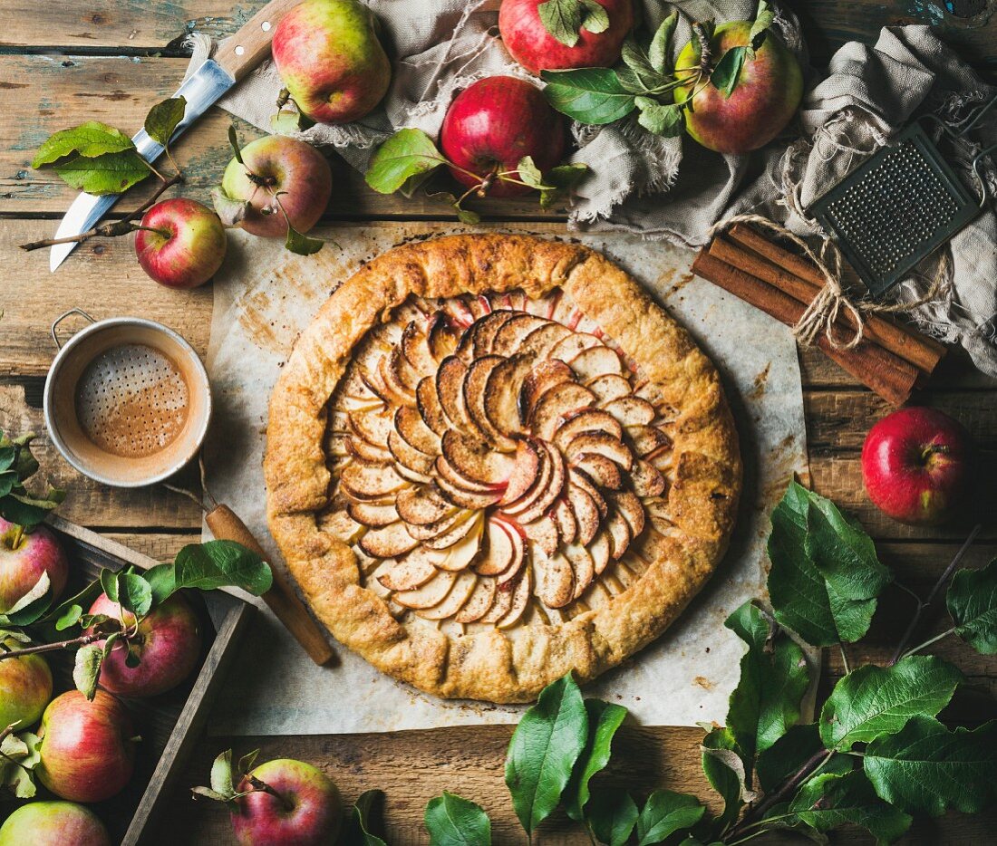 Apple crostata pie with cinnamon served with fresh garden apples with leaves on rustic wooden background