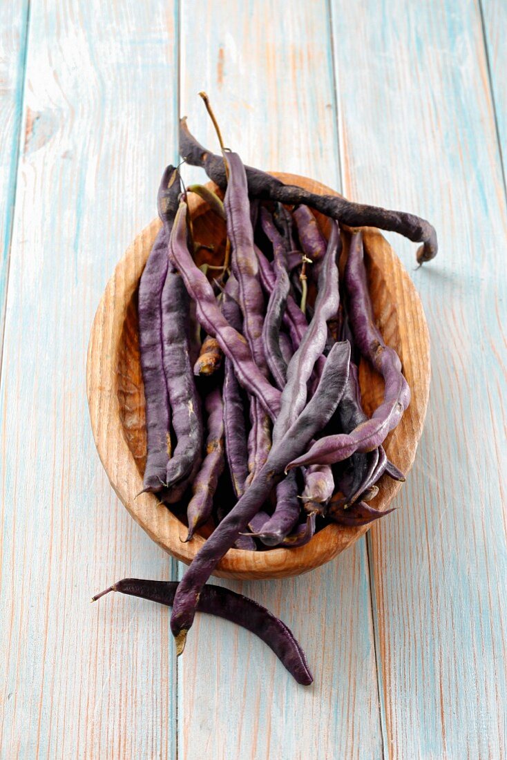 Purple beans in a wooden bowl