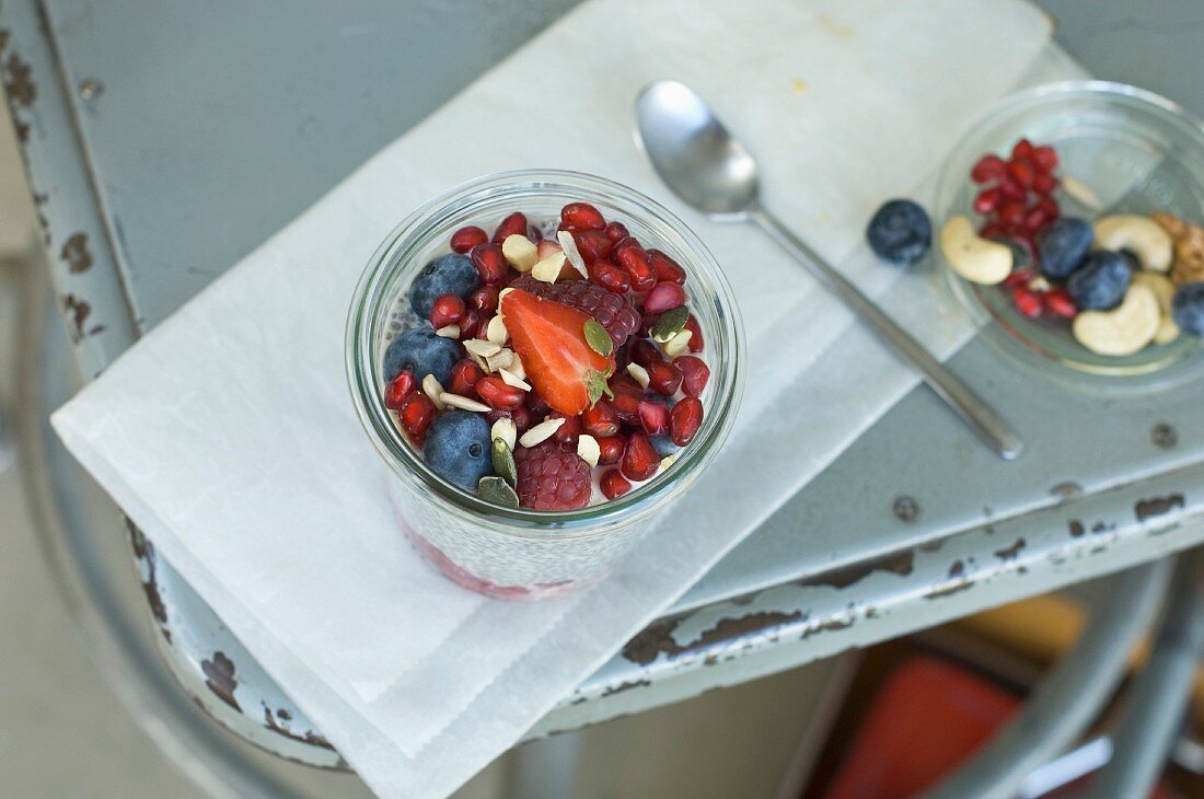 Chia pudding with summer fruits and nuts in a glass on an old chair