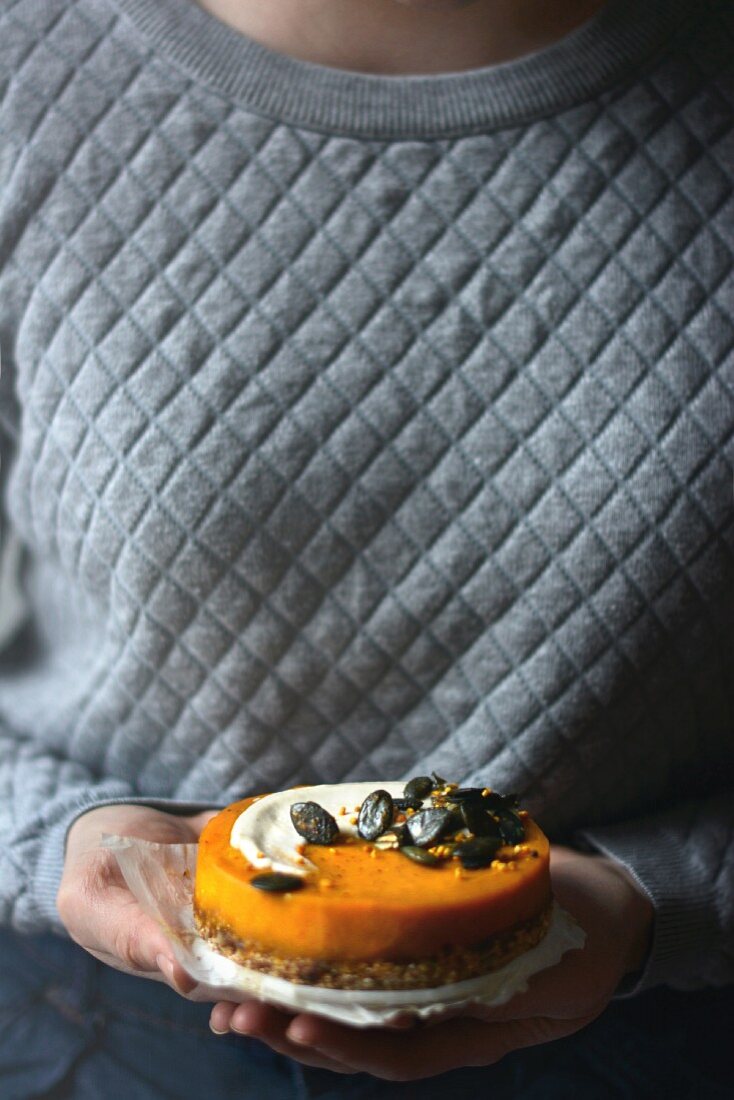 A vegan pumpkin cake with cashew cream and caramelised pumpkin seeds