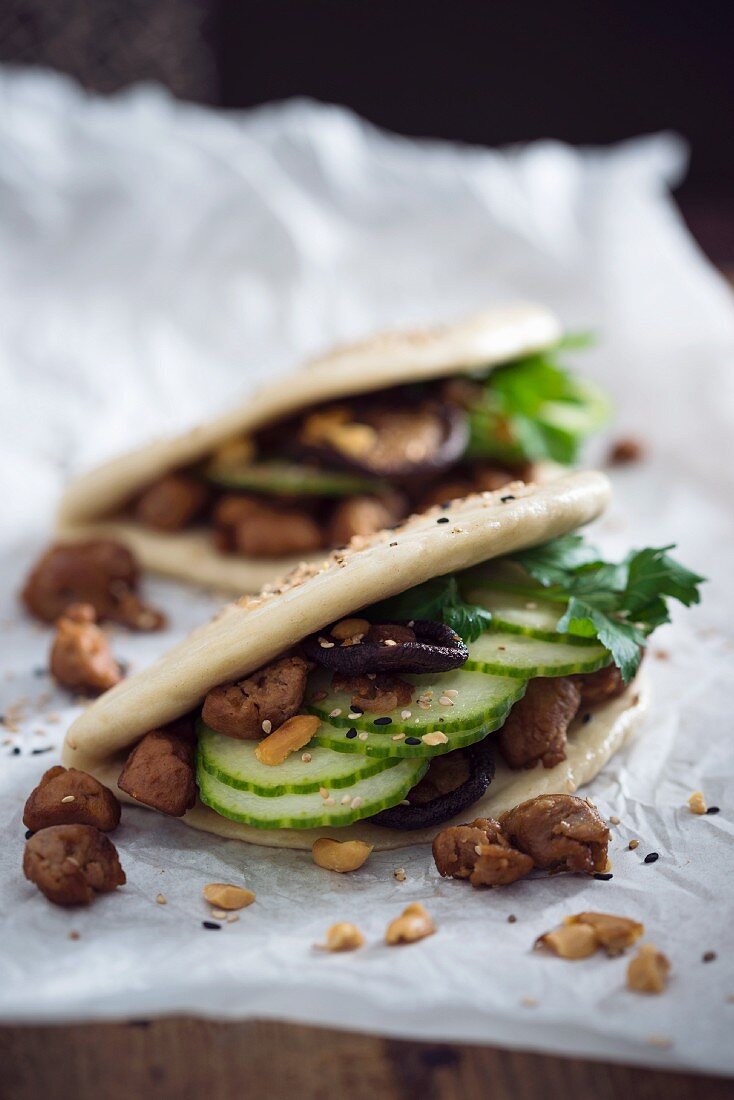 Vegan bao tacos with soya strips, cucumber, shiitake mushrooms, roasted peanuts and sesame seeds