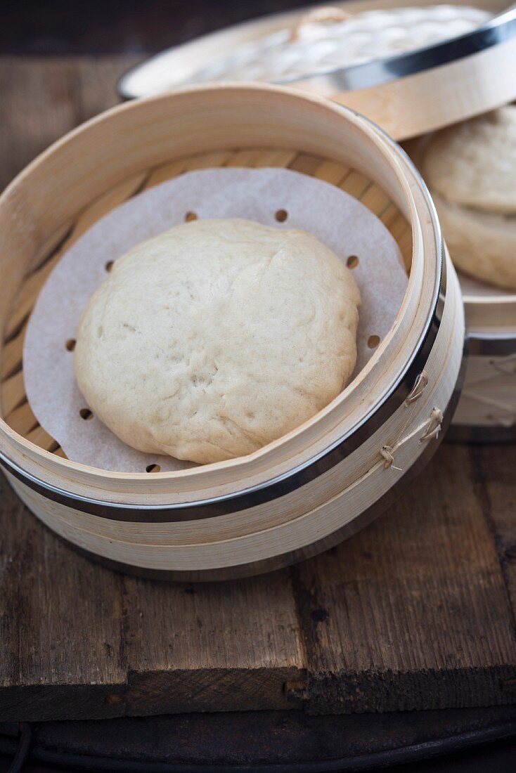 A bao bun in a bamboo steamer