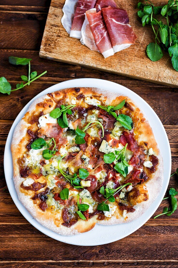 Homemade pizza with blue cheese, pancetta, onion chutney and lamb's lettuce