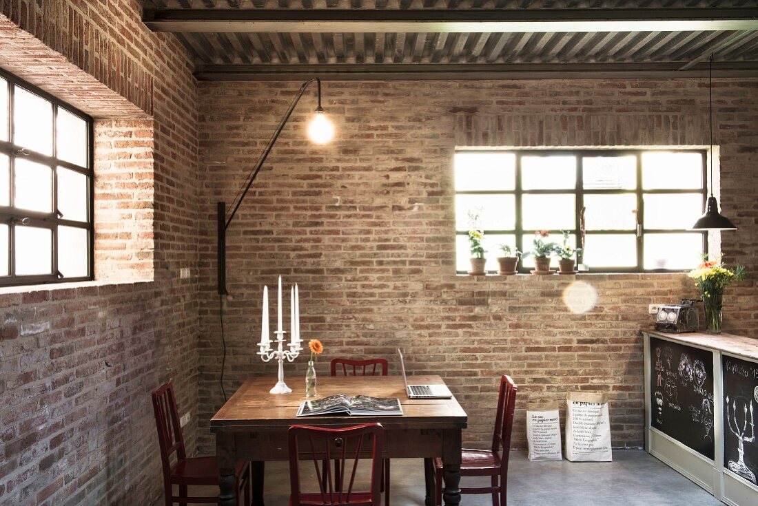 Candlesticks and laptop in illuminated dining area with brick walls in converted stable