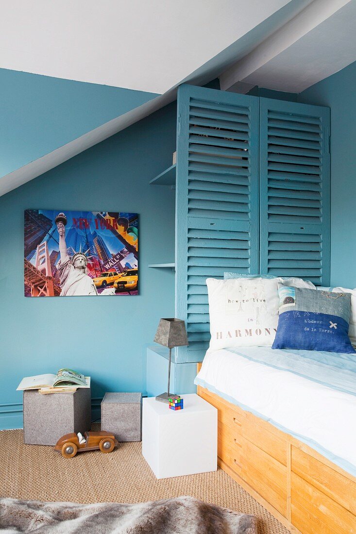 Petrol-blue walls and shelves behind slatted screen in boy's bedroom