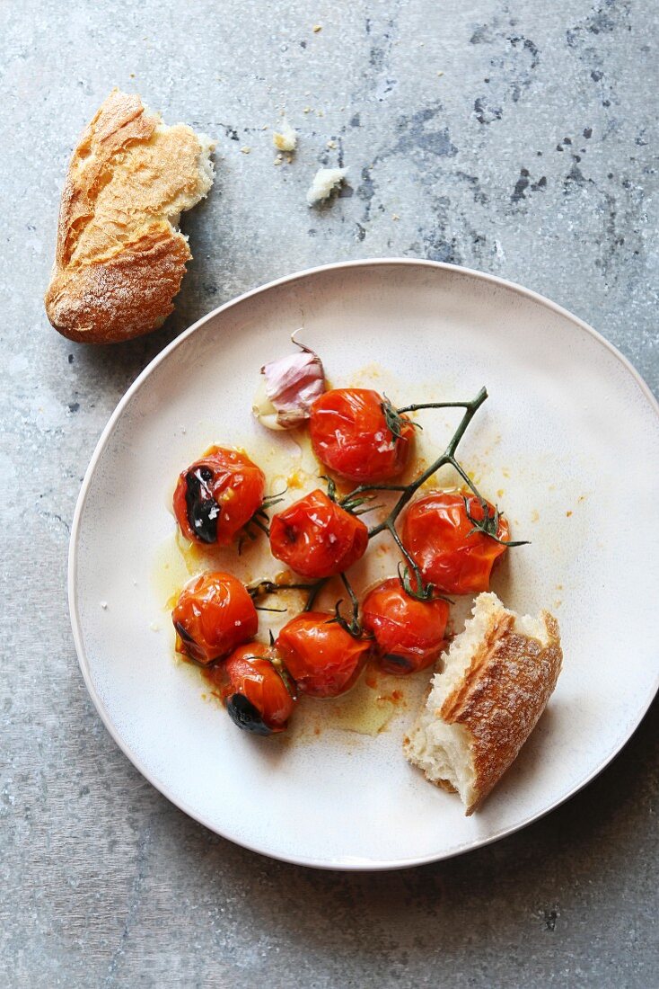 Roasted cherry tomato with olive oil and sea salt on a white plate