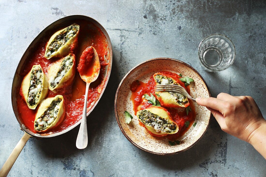 Female eating stuffed pasta shells with ricotta cheese and spinach