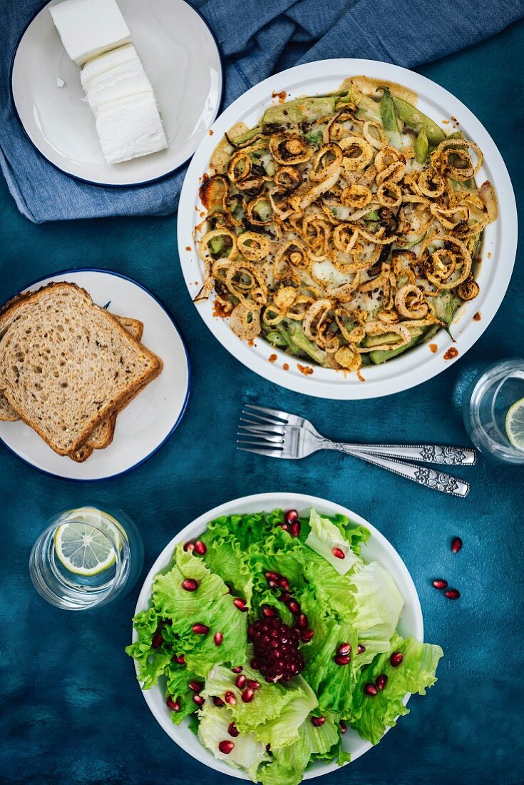 Grüner Bohneneintopf mit Zwiebelringen und Pilzen, serviert mit Salat, Brot und Käse