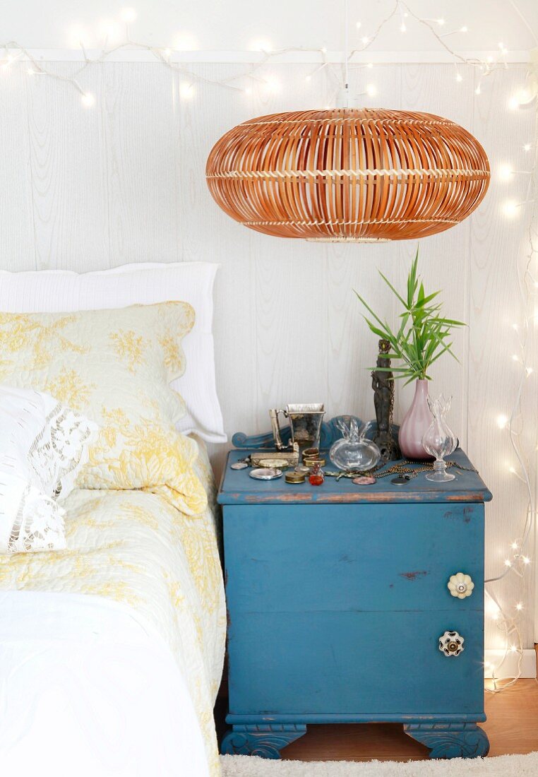 Old, blue, shabby-chic bedside cabinet against board wall