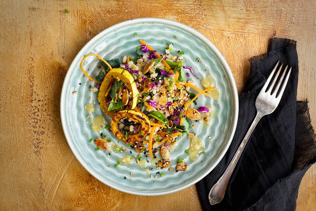 Sesam-Dinkel-Salat mit Delicata- Kürbis, serviert mit Dressing, gerösteten Nüssen und Schnittlauch