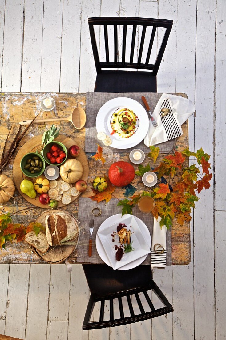 Herbstlich gedeckter Tisch mit Kürbis- und Blätterdekoration (Aufsicht)