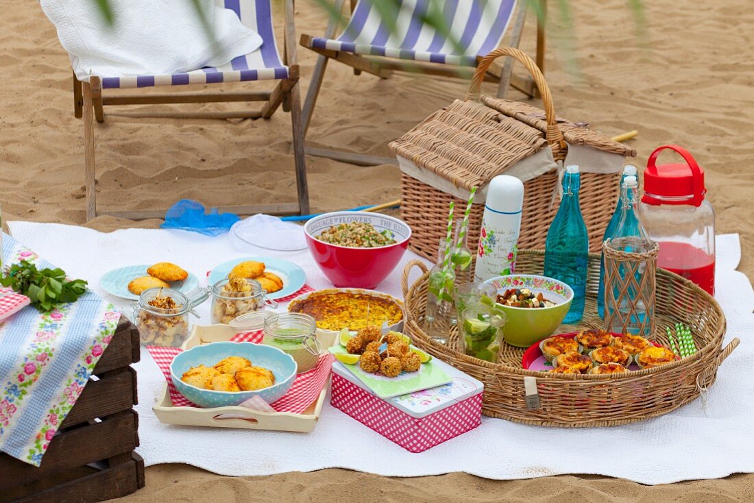 A picnic on a sandy beach with various nibbles and drinks