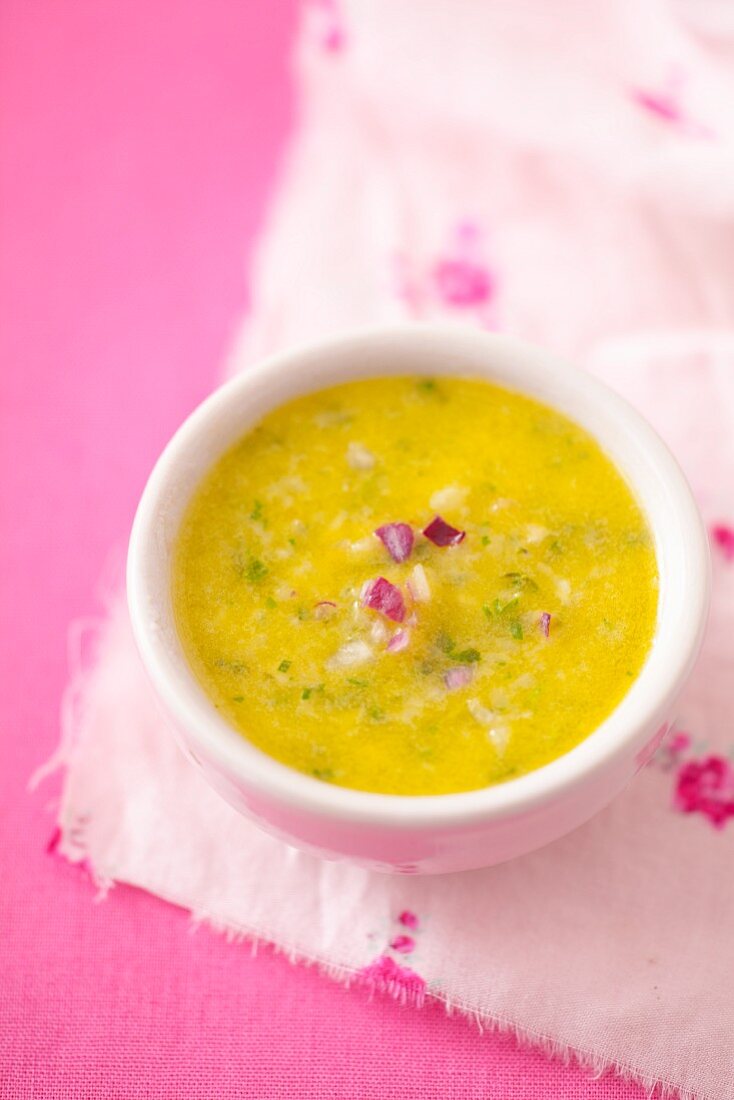 A bowl of salad dressing with olive oil and red onion