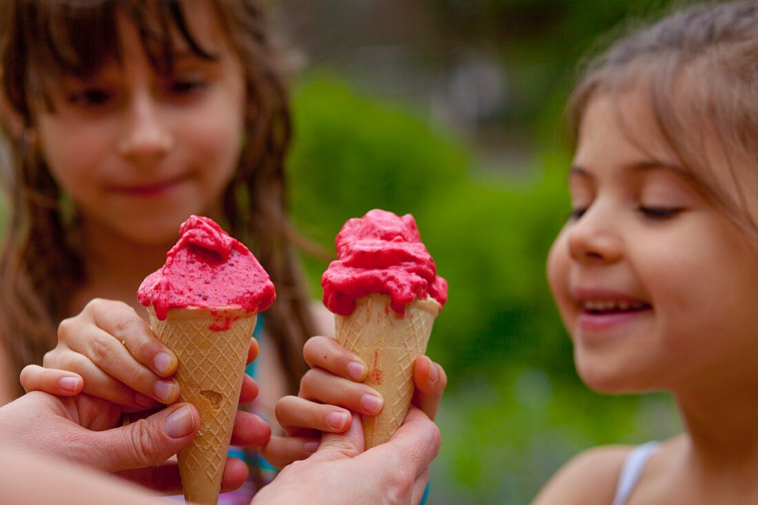 Two girls eating waffle cones with strawberry sorbet