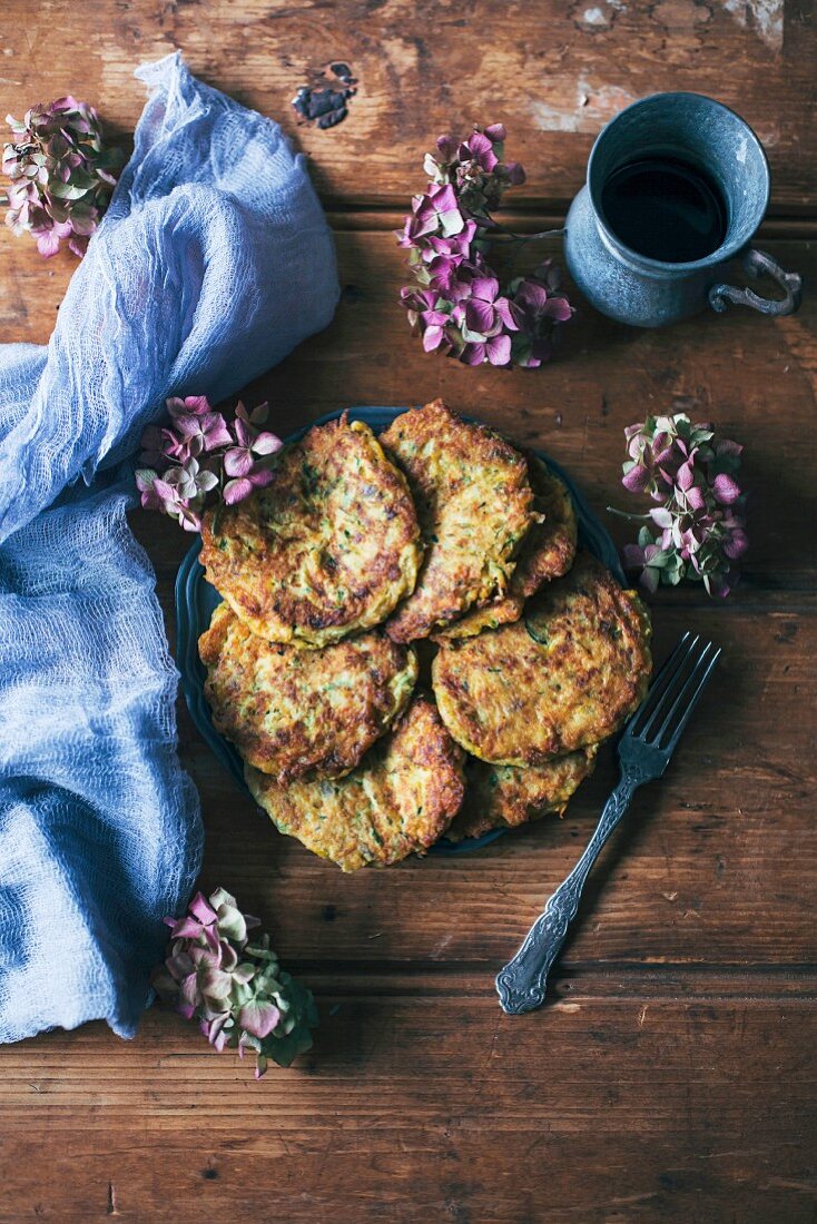 Zucchini, carrot and cheese fritters on a plate on rustic wooden table