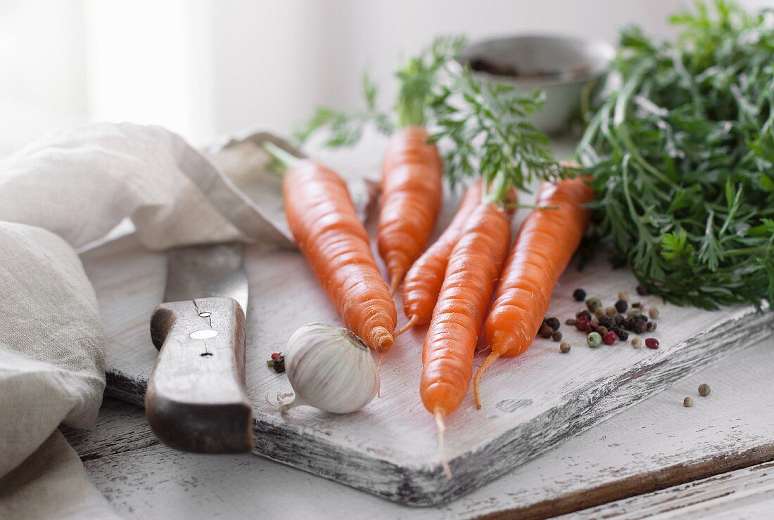 Fresh carrots with garlic and pepper on a chopping board
