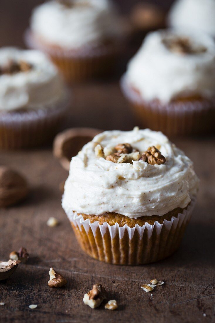 Pumpkin cupcake with cream cheese frosting and walnuts.