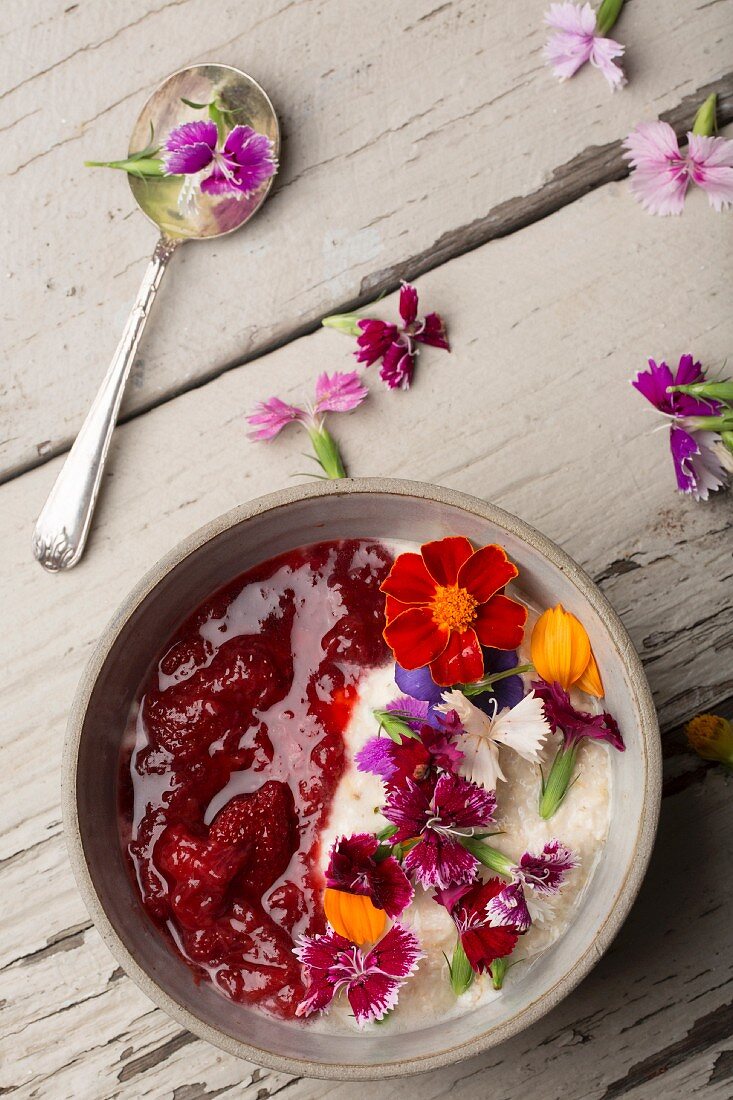 A breakfast of porridge with strawberry compote and fresh edible flowers (seen from above)