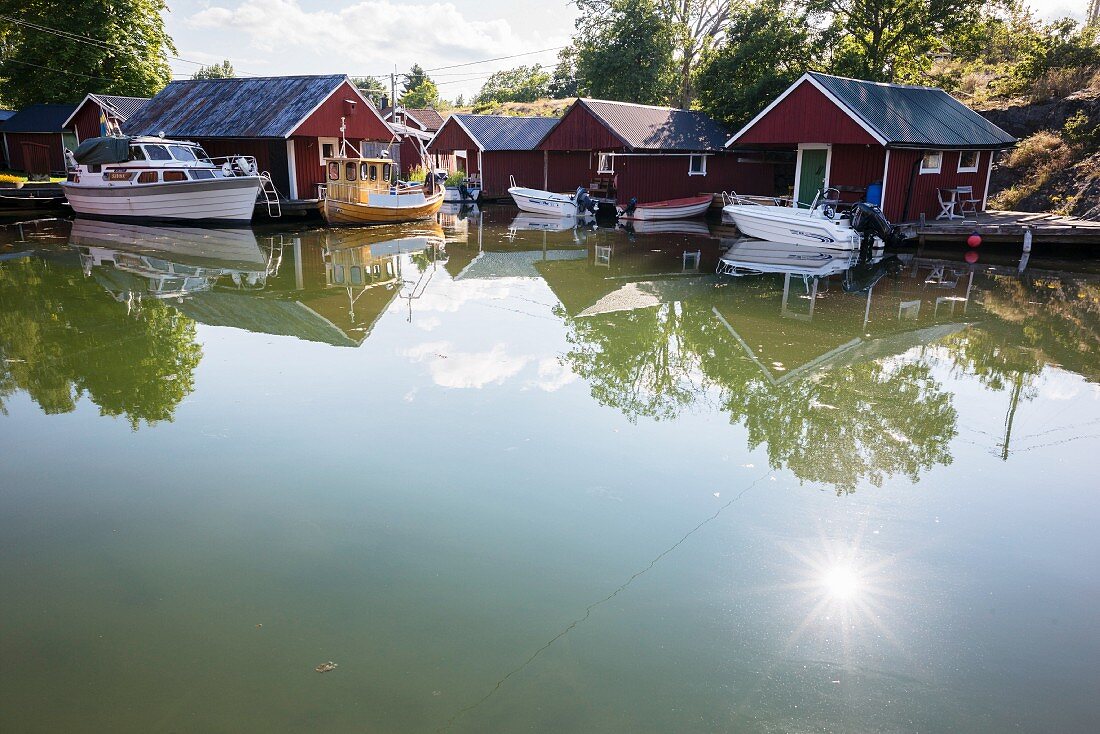 Motorboote vor Holzhütten am See, Südschweden