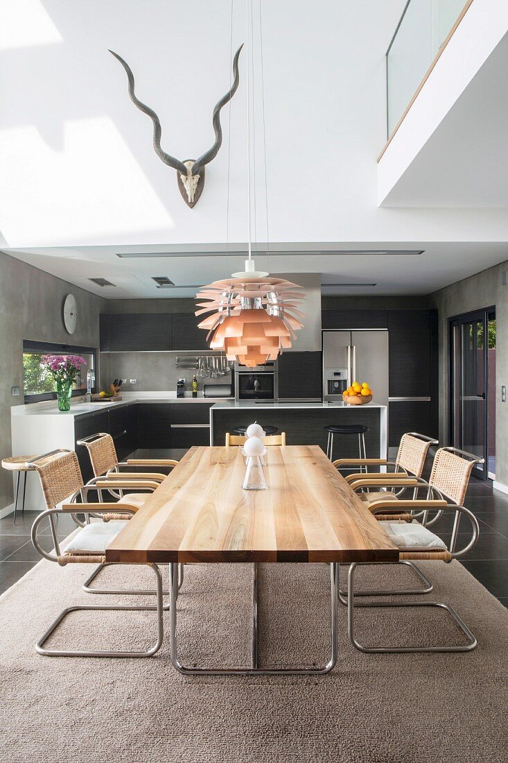 Moderner Esstisch mit Schwingstühlen vor offener Küche