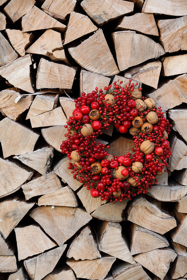 Roter Beerenkranz mit Walnüssen und Mispeln am Holzlager