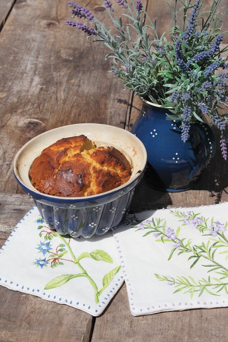 Hand-made pot holders and cake and lavender in ceramic vessels on wooden table