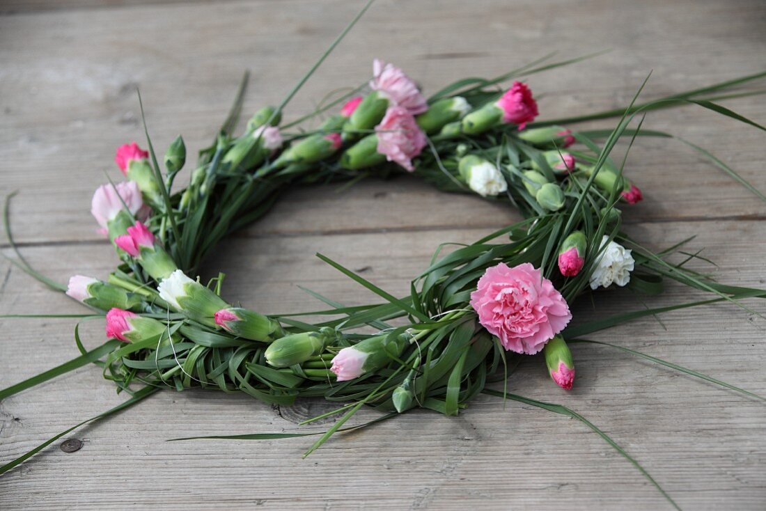 Wreath of carnations on wooden surface