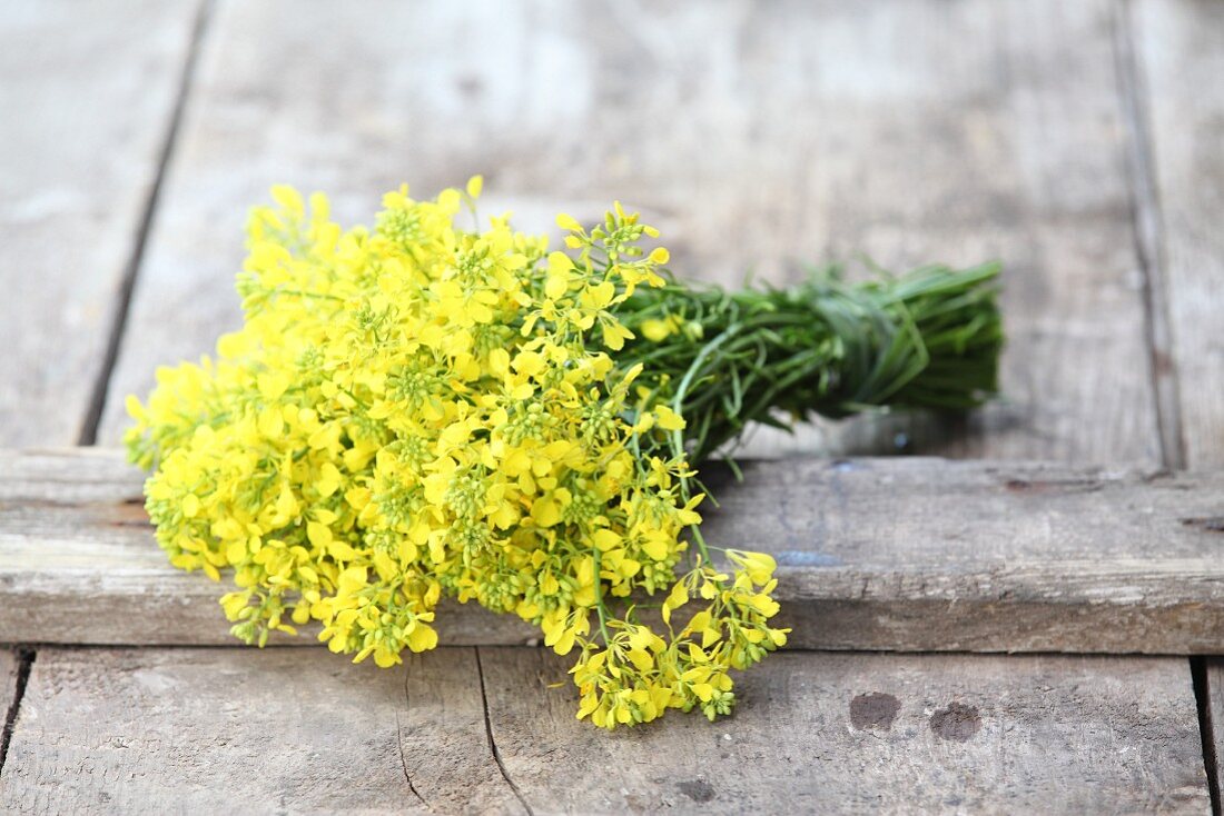 Bunch of rapeseed flowers on wooden boards