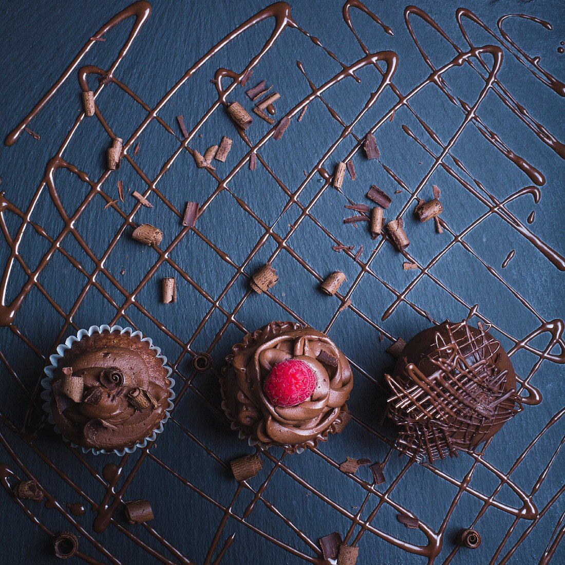 Decadent chocolate cupcakes with chocolate icing, shavings of chocolate and a raspberry