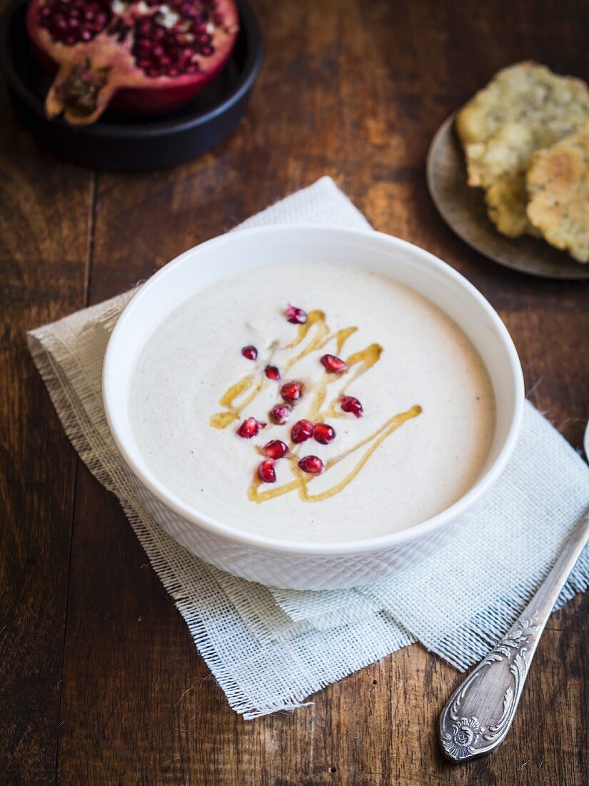Cream couliflour soup served with tahina sauce and pomegranate seeds